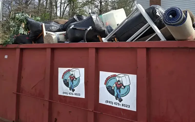 Red dumpster filled with furniture, rugs and household cleanout debris