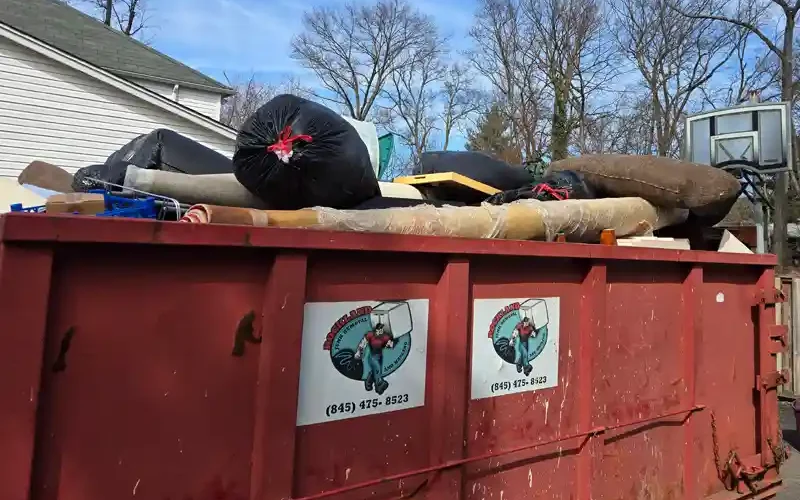 Red dumpster filled with furniture and household items during a full house cleanout
